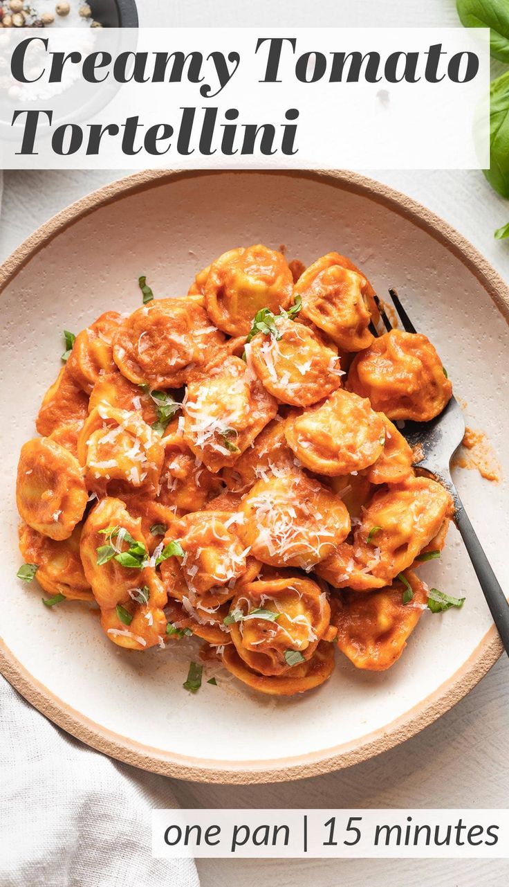 a white bowl filled with pasta and sauce on top of a table next to a fork