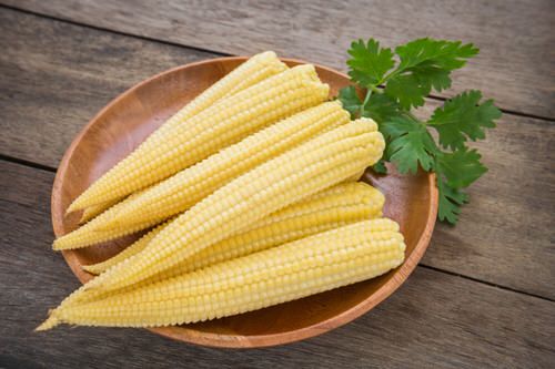 corn on the cob in a wooden bowl with parsley