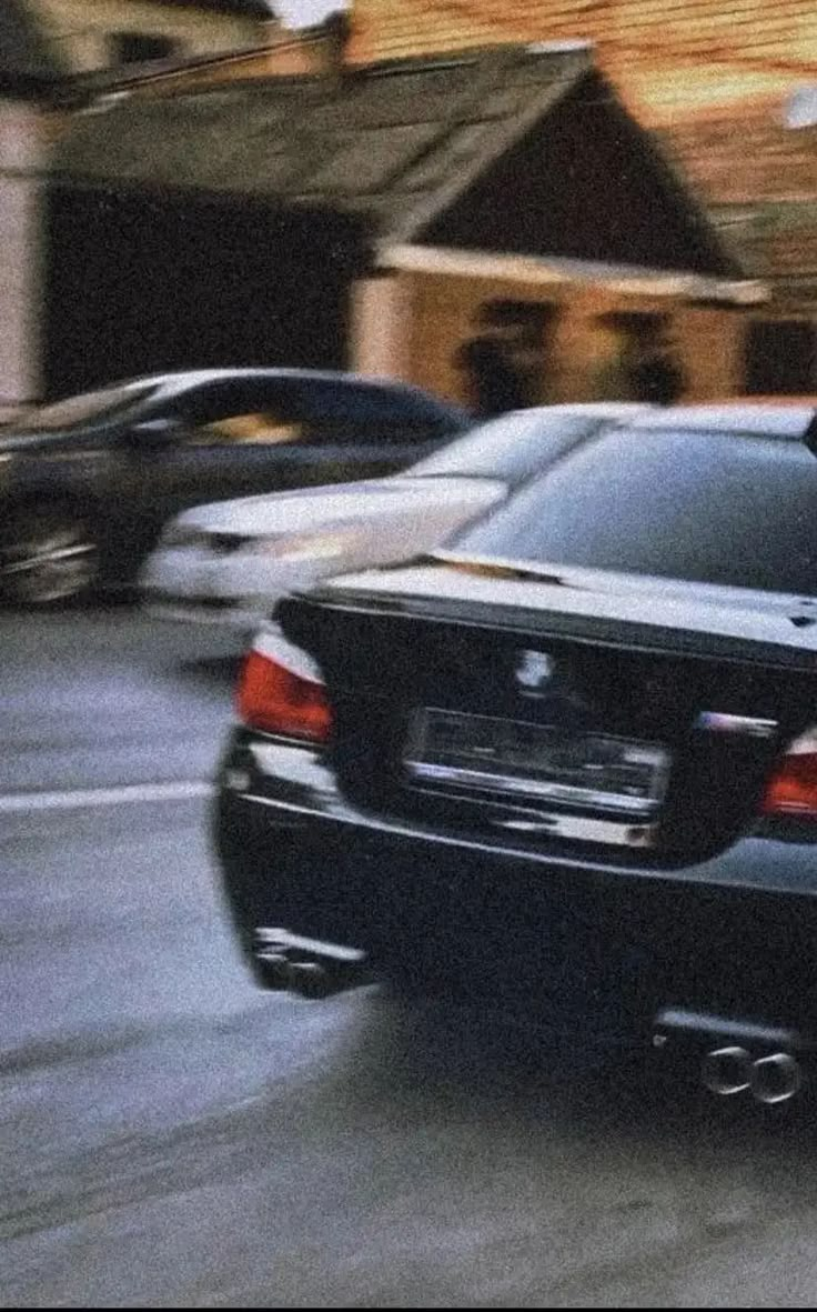 a black car driving down a street next to tall buildings