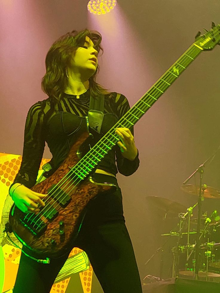 a woman holding a guitar on stage at a concert