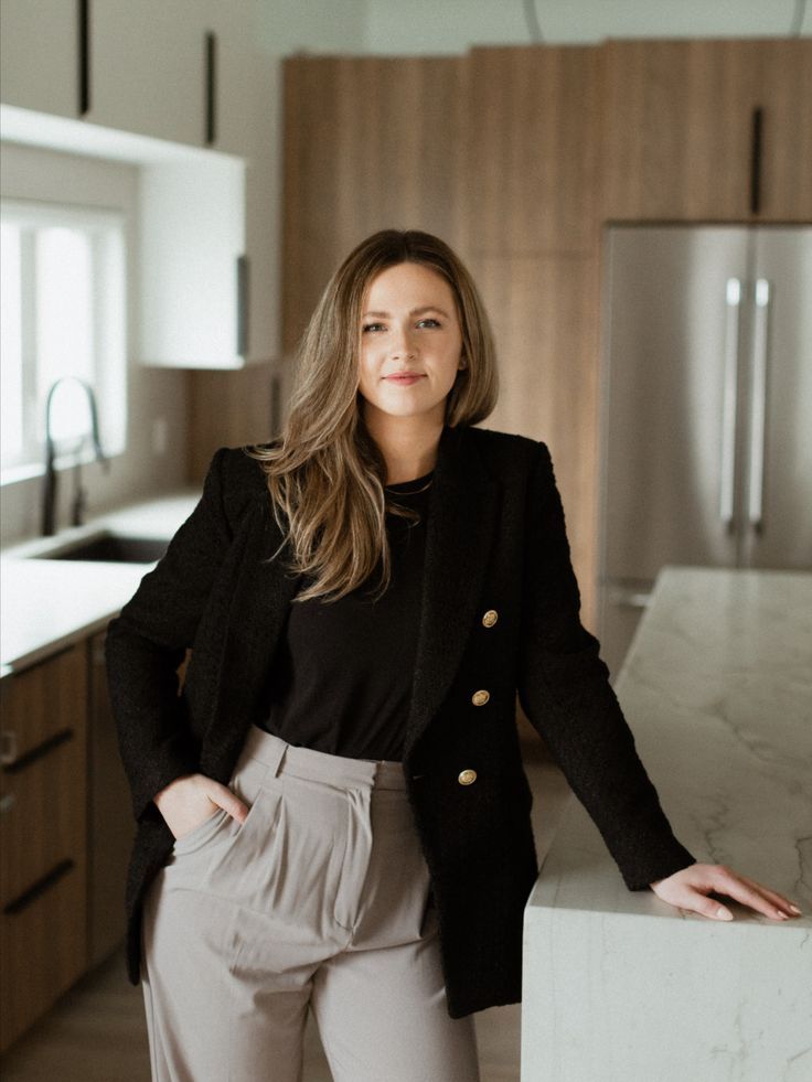 a woman standing next to a counter in a kitchen with wooden cabinets and white counters