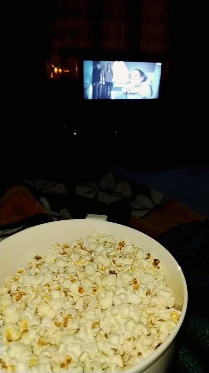 a white bowl filled with popcorn in front of a tv