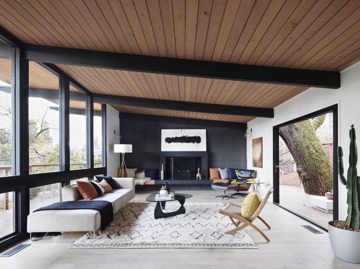 a living room filled with furniture next to a large glass window covered in wood planks