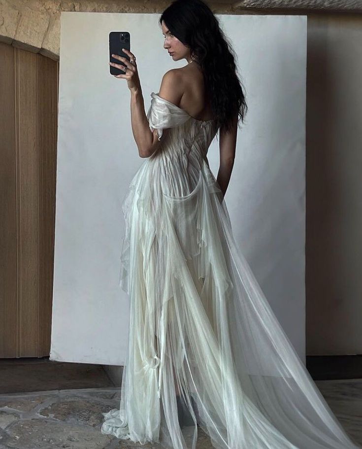 a woman in a white dress holding a cell phone