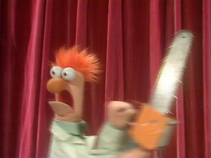 the puppet shows an orange haired man holding a large knife in front of red curtains