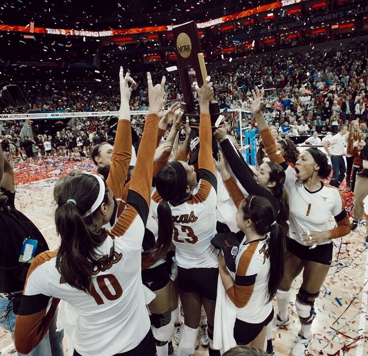 women's volleyball team celebrating with trophy