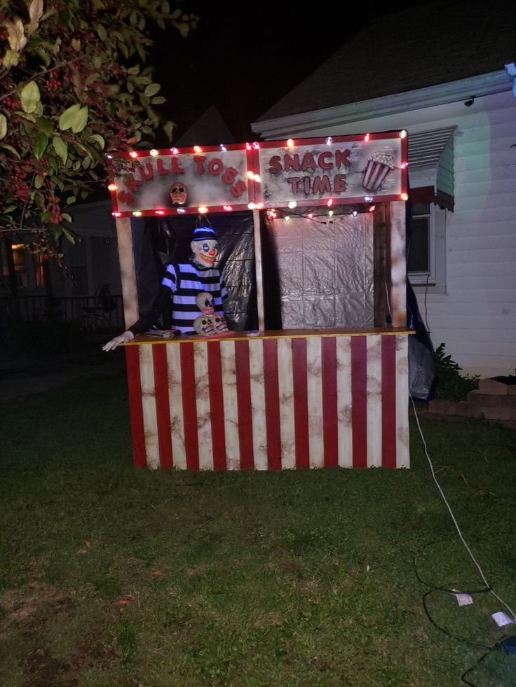 a man standing in front of a carnival booth with lights on it's sides