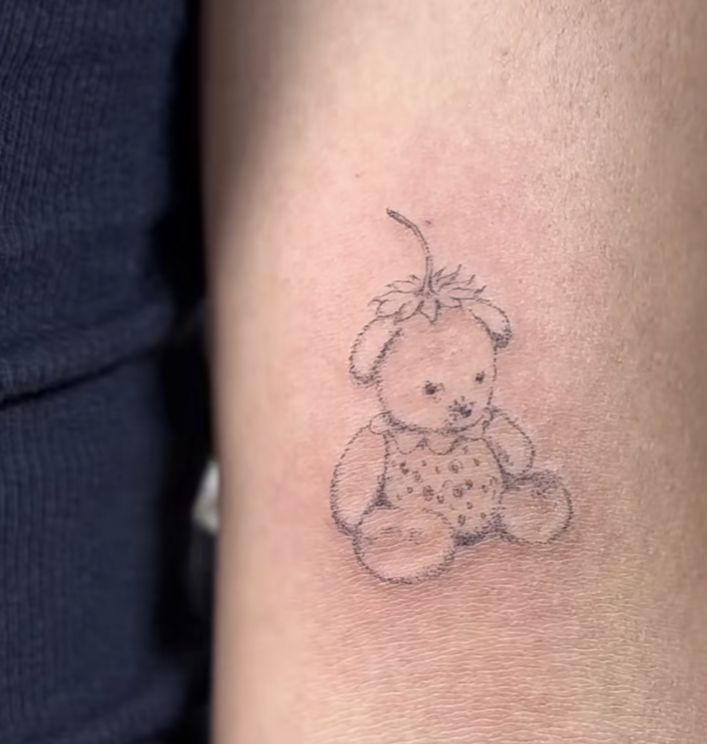 a small teddy bear tattoo on the arm