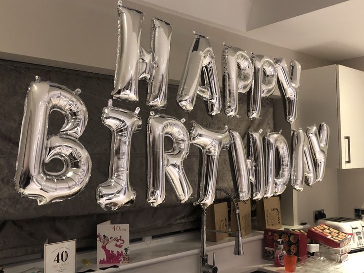 some balloons that say happy birthday are hanging on the wall in front of a kitchen counter