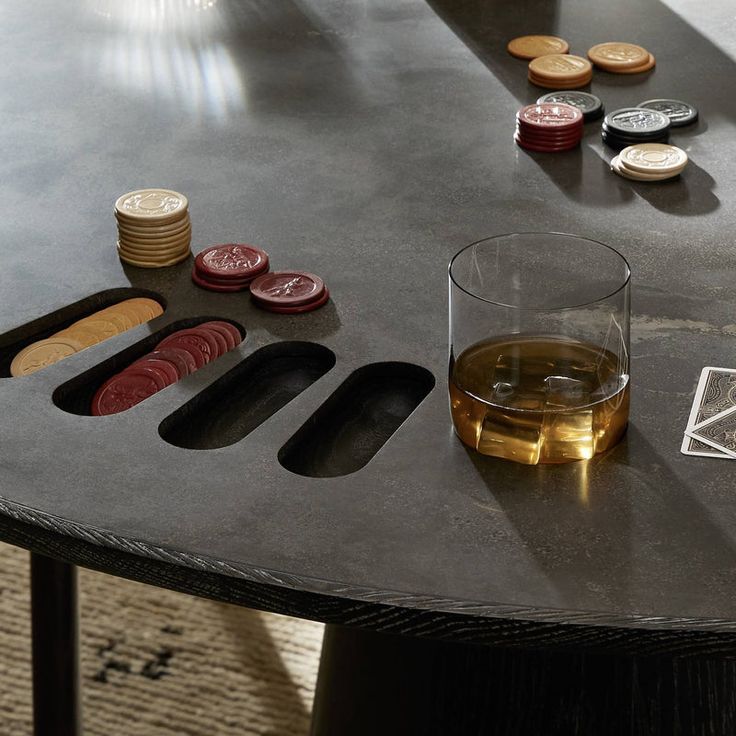 a glass of alcohol sitting on top of a table next to some coins and playing cards