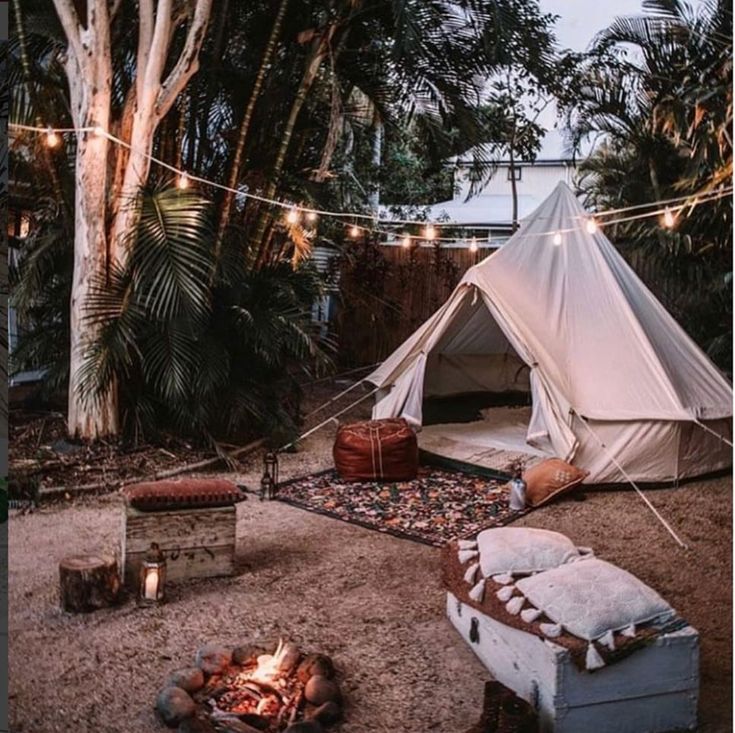 a tent is set up in the middle of a yard with lights strung over it