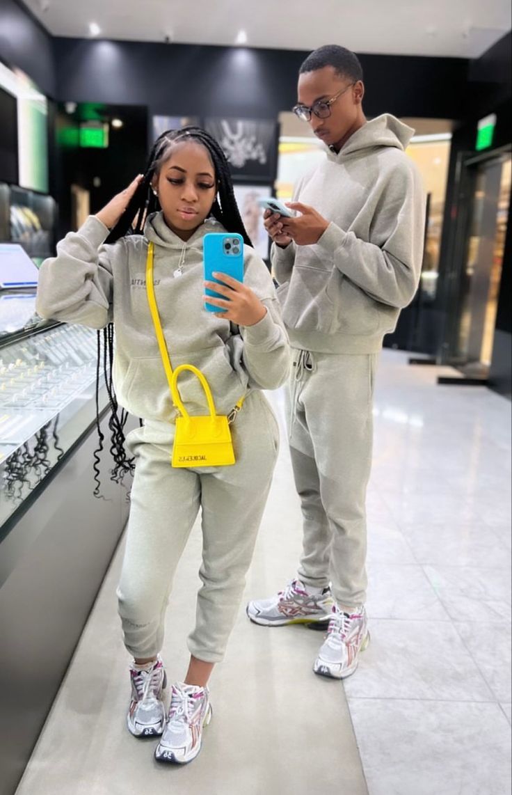 a man and woman looking at their cell phones in a store with one holding a yellow handbag