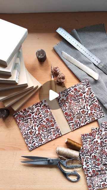 some fabric and scissors are laying on a table with other crafting supplies such as paper