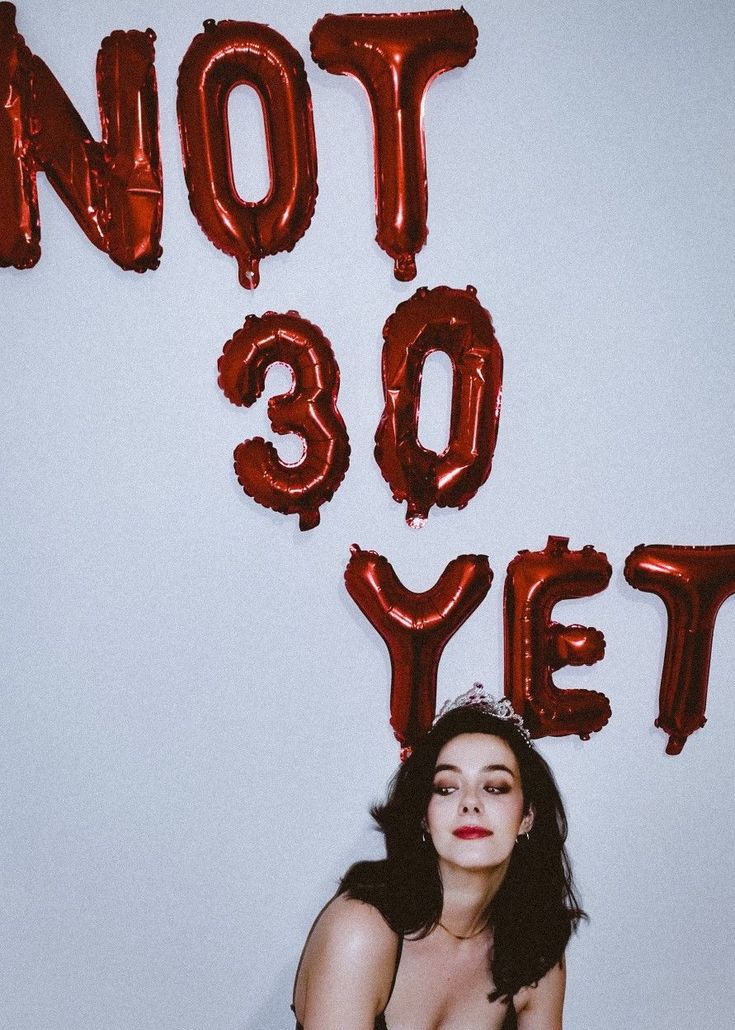 a woman sitting on the floor in front of balloons that say not 90 yeet