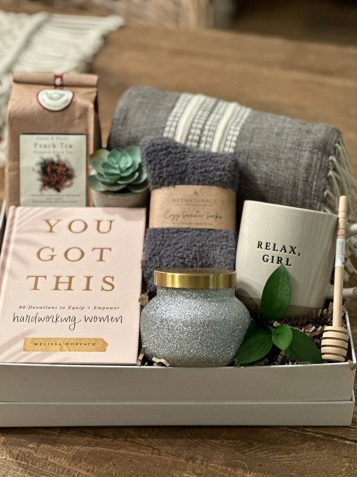 a gift box filled with books, candles and other items on top of a wooden table