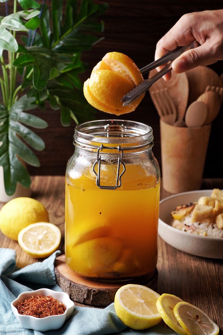 someone is squeezing lemons into a mason jar