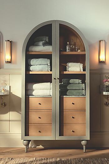 a bathroom with an arch shaped cabinet in the center and towels on it's sides