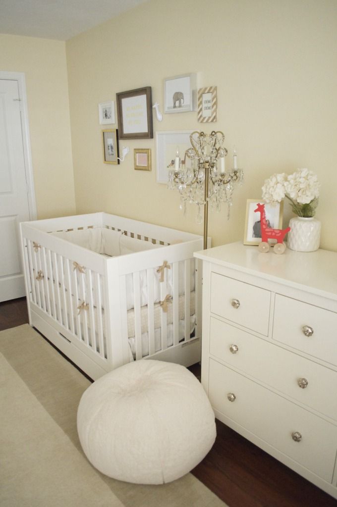 a baby's room with a white crib, dresser and chandelier