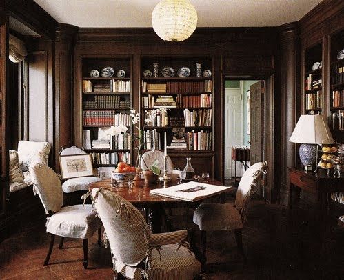 a room with many bookshelves and chairs around a table in front of a bookcase