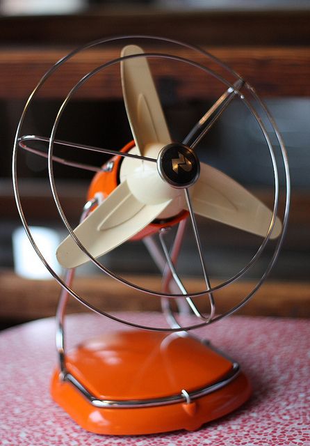 an orange table with a metal fan on it