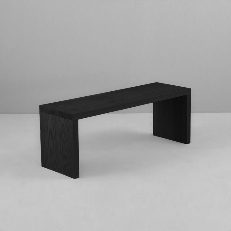 a black bench sitting on top of a white floor in front of a gray wall