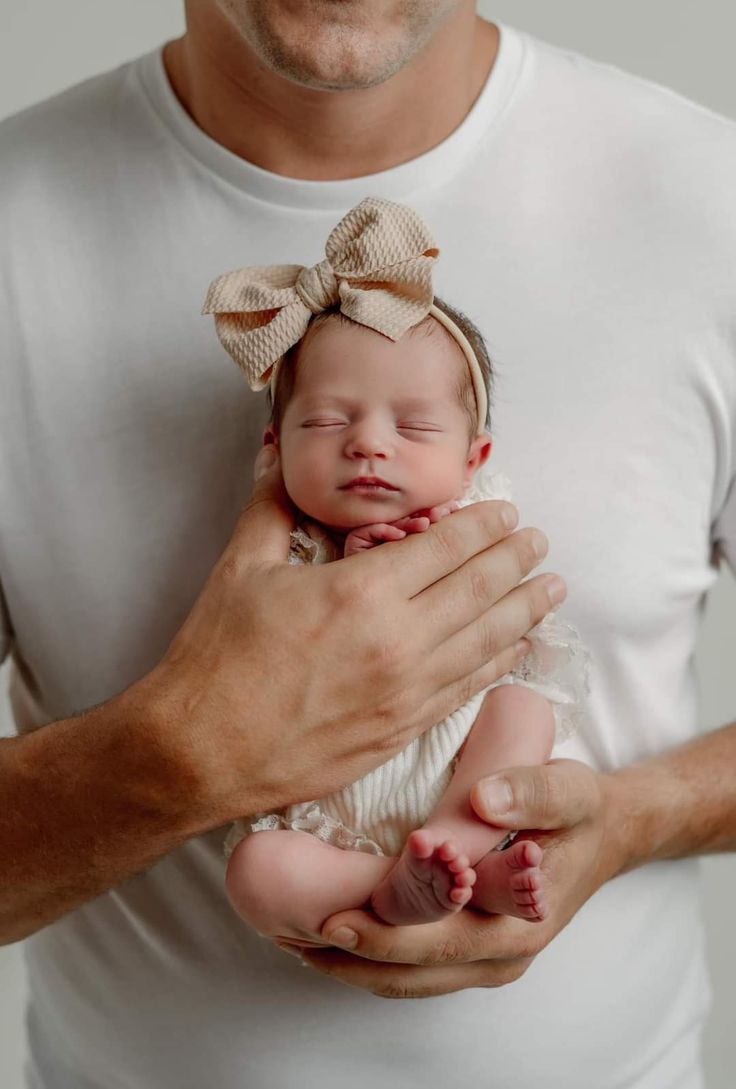 a man holding a baby in his arms and wearing a bow on it's head