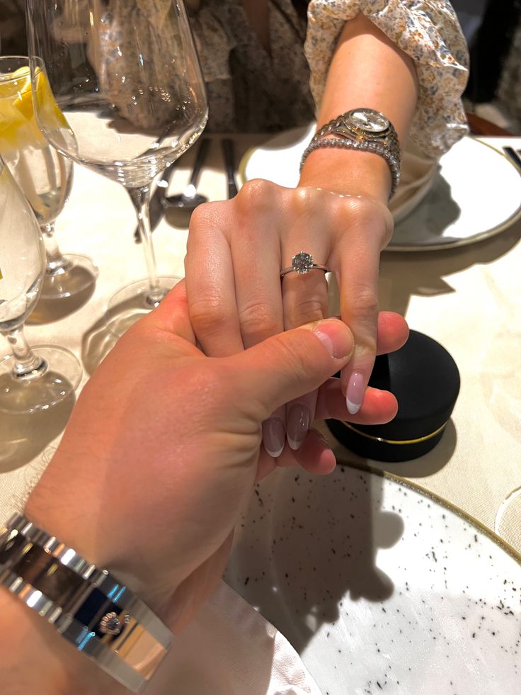 two people holding hands at a table with wine glasses