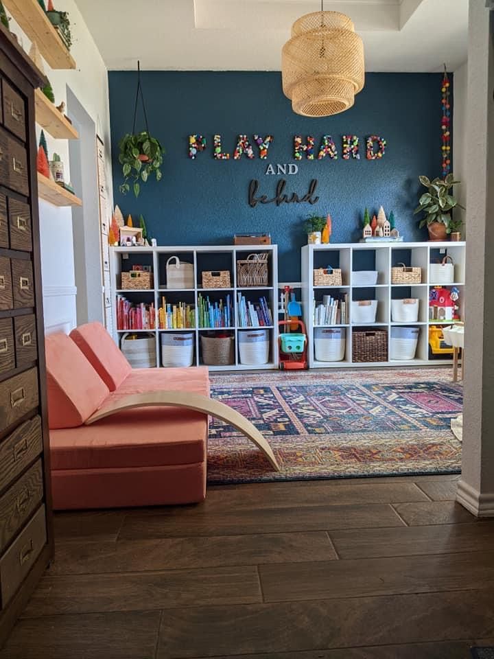 a living room filled with furniture and bookshelves next to a wall that says play hard and love