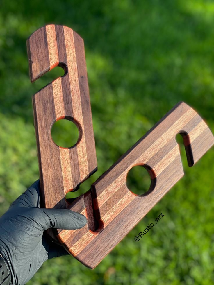 a hand holding two pieces of wood with holes in them