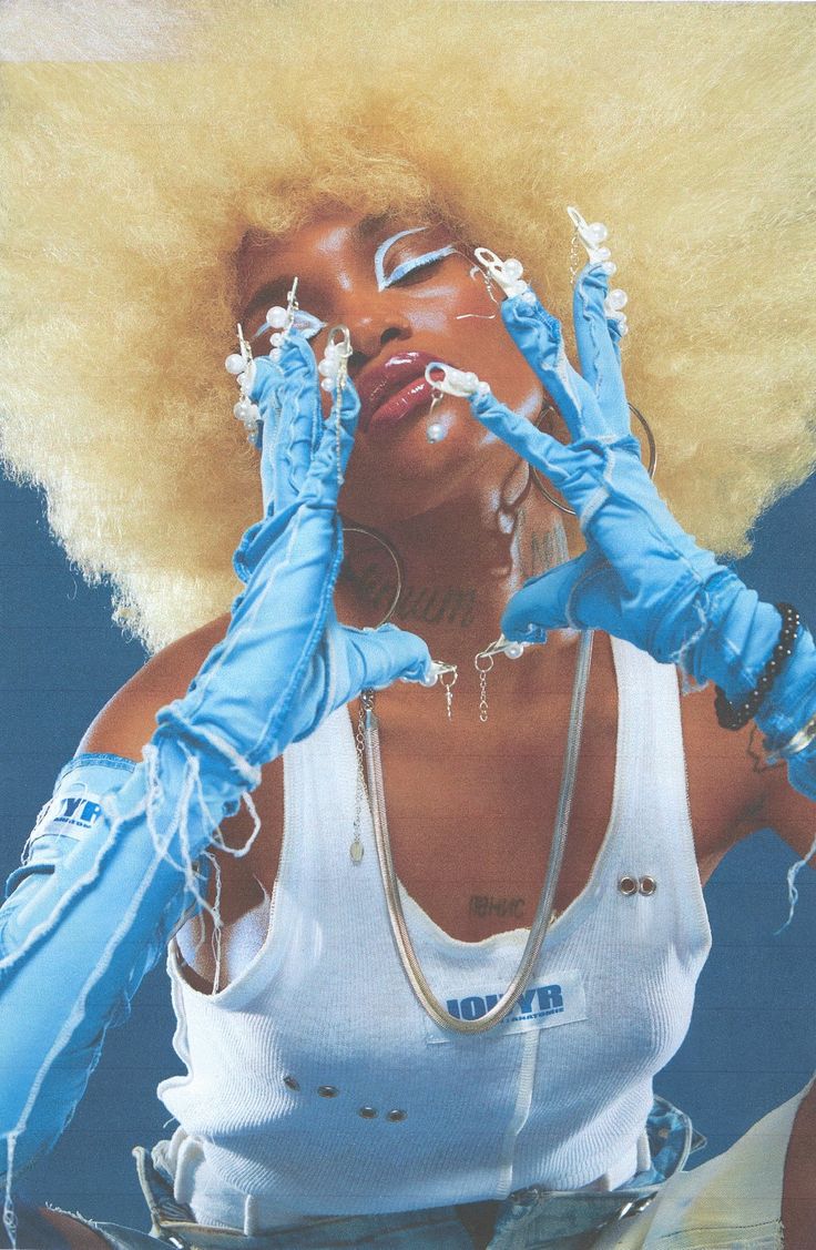 a woman wearing blue gloves and holding her hands up in front of her face with an afro hairstyle