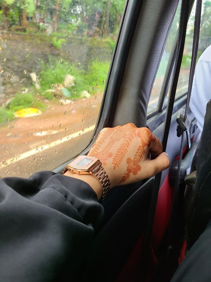 a person is sitting in a car with their hand on the steering wheel while holding onto an orange wrist watch