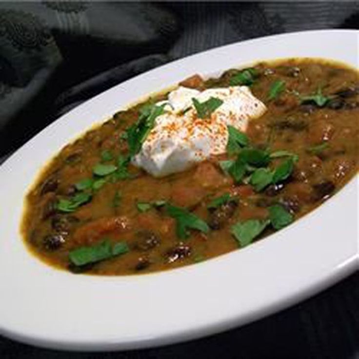 a white bowl filled with soup and sour cream on top of a black tablecloth