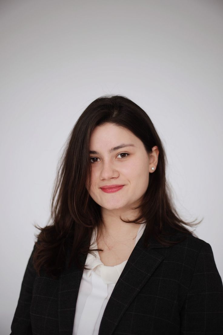 a woman with long hair wearing a black blazer and white shirt is smiling at the camera