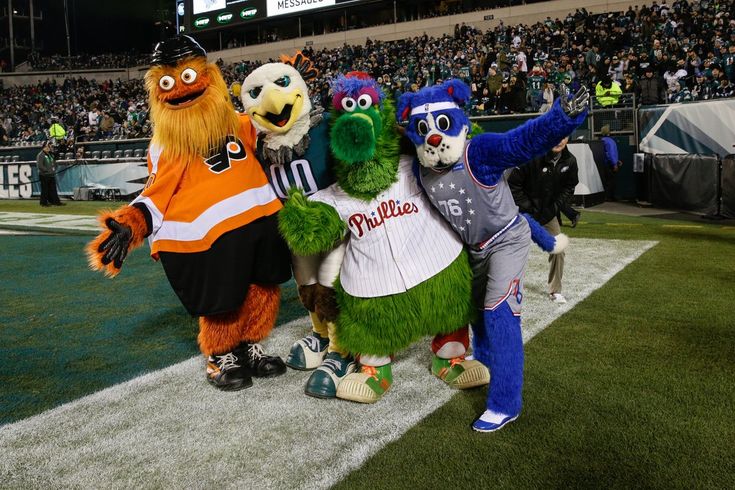 the philadelphia phillies mascot poses for a photo with other mascot on the sidelines at an outdoor baseball game