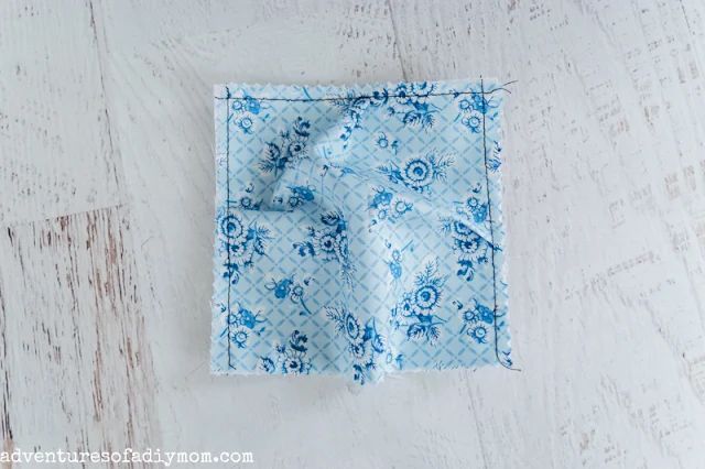 a blue and white flowered cloth on top of a wooden table with a knot in the middle