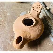 a clay vase sitting on top of a wooden table next to a wall and floor