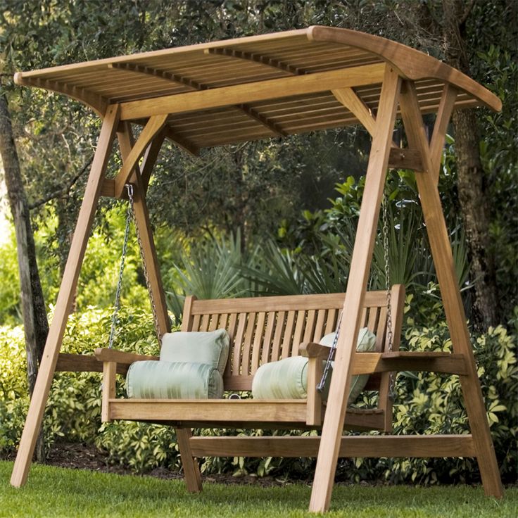 a wooden swing bench sitting in the grass