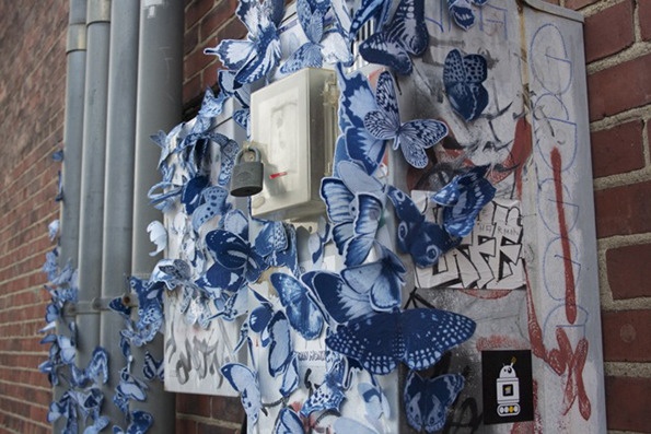 blue and white butterflies hang on the side of a building in front of a brick wall