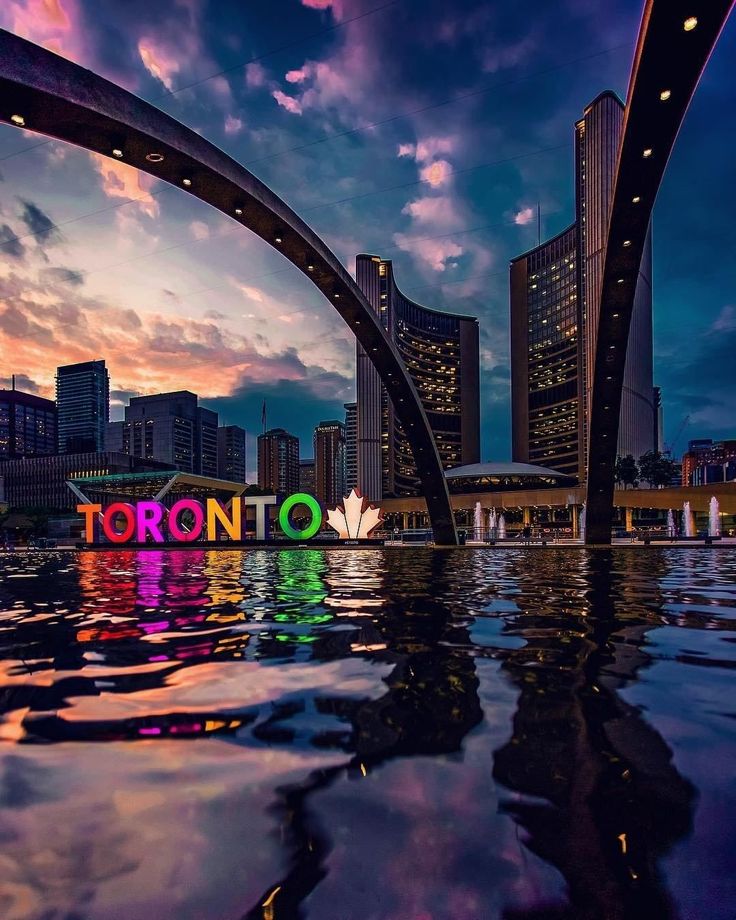 the word toronto is reflected in the water at sunset with skyscrapers in the background