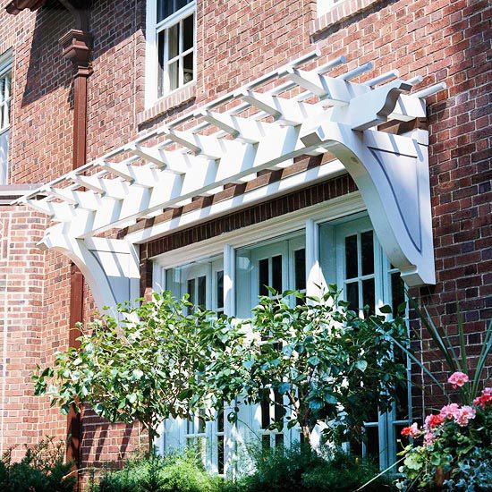 a brick building with a white awning over it's windows and flowers in the foreground