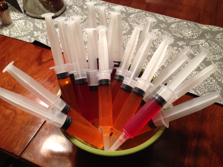 a green bowl filled with lots of different colored liquid bottles on top of a wooden table