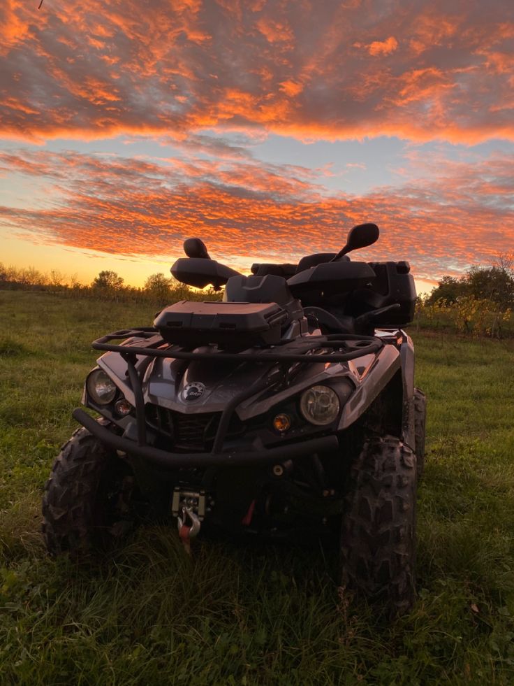 an atv is parked in the grass at sunset