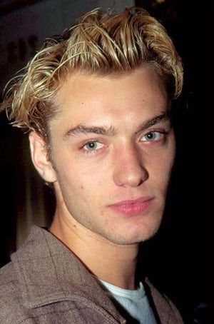 a man with blonde hair and blue eyes looks at the camera while wearing a jacket