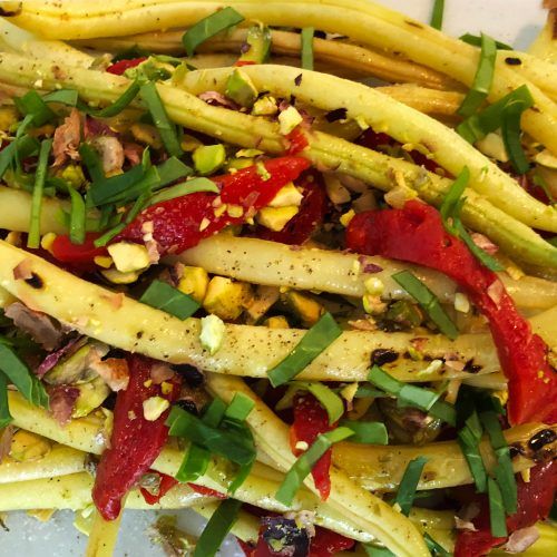 a white plate topped with green beans and red peppers