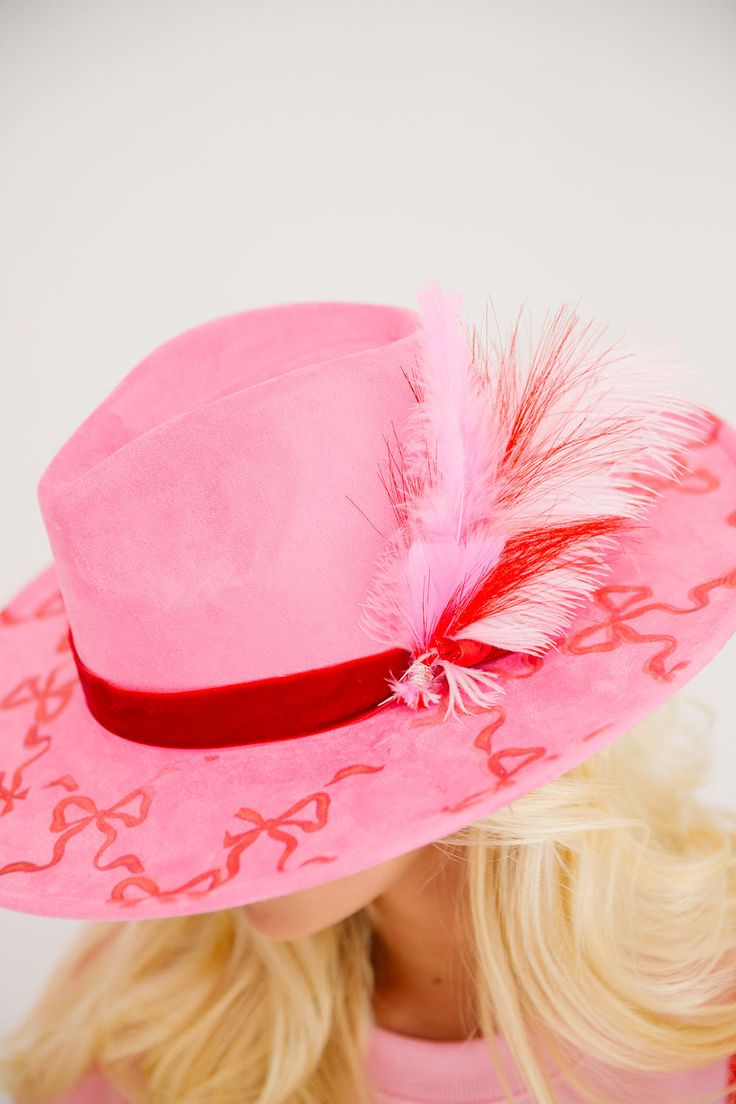 Unleash your inner cowgirl cutie with our WRAP SEASON PINK RANCHER HAT. Featuring a playful red bows print and a luxurious red velvet band, this pink hat is sure to turn heads. Plus, the added touch of pink, red, and white feathers adds a fun and unique flair. Saddle up and make a statement today! This hat is ONE OF A KIND, created by our owner Stephanie. To receive item quicker, expedited shipping is available at checkout. Pink Felt Hat With Curved Brim For Kentucky Derby, Pink Curved Brim Felt Hat For Kentucky Derby, Pink Fedora Felt Hat For Kentucky Derby, Pink Fedora For Kentucky Derby, Pink Fedora For Party, Pink Felt Hat With Curved Brim For Party, Pink Fedora With Flat Brim For Party, Pink Fitted Fedora For Kentucky Derby, Pink Flat Brim Fedora For Party