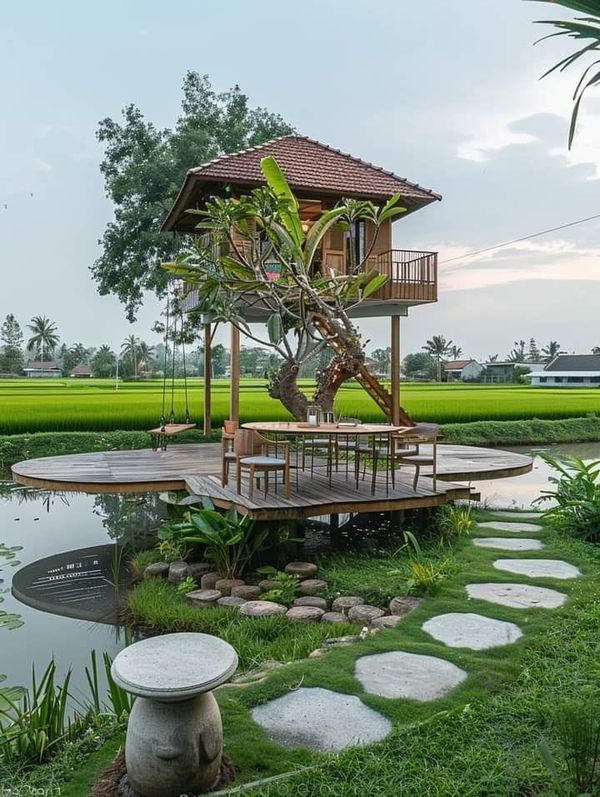 a tree house sitting on top of a lush green field next to a small pond