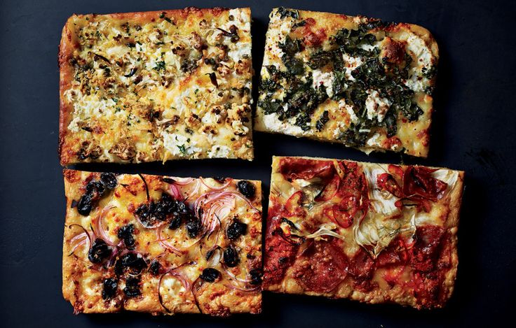 four square pizzas with different toppings sitting on top of a black countertop