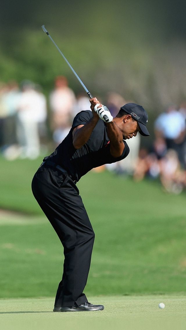 the man is playing golf in front of a large group of people on the field