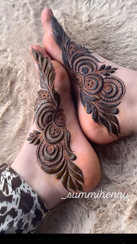 two feet with henna tattoos on them and one has an intricate design in the middle