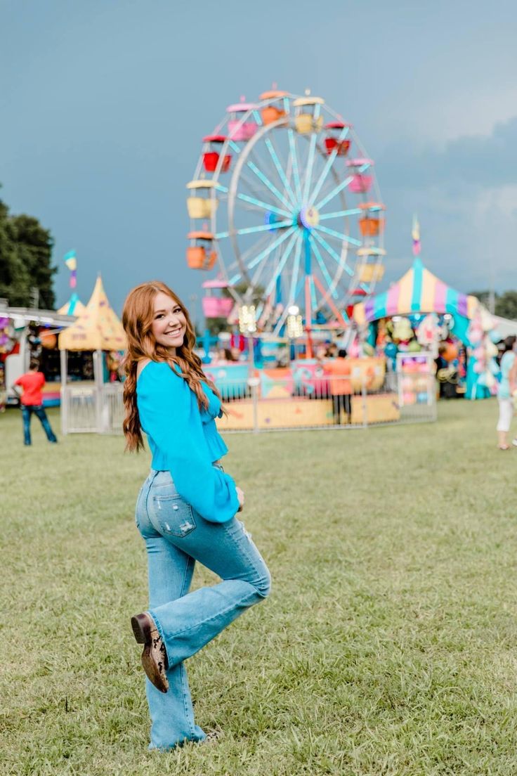 a woman is posing in front of a carnival